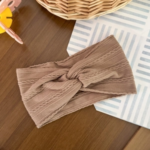 Detail of vintage ribbed knit headband with twist knot pattern on a wooden surface