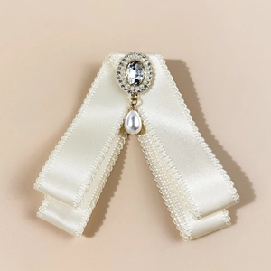 Detail of cream satin bow tie with crystal center and elegant pearl drop tassel