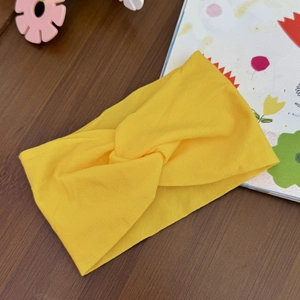 Close-up of bright yellow elastic knot headband on a rustic wooden surface background