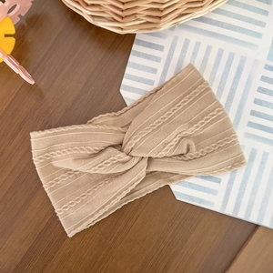 Detail of light beige cable knit elastic headband with a stylish central twist design