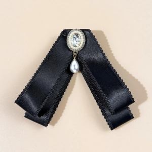 Detailed view of a vintage black satin bow brooch with rhinestone and teardrop pearl
