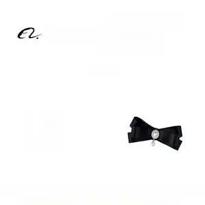 Detail view of a black silk bow brooch with sparkling rhinestones and a pearl pendant charm