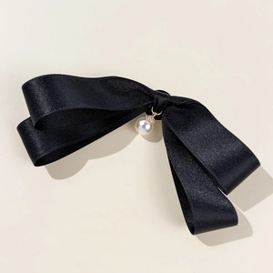 Close-up of black satin bow tie with elegant white pearl pendant for JK school uniform