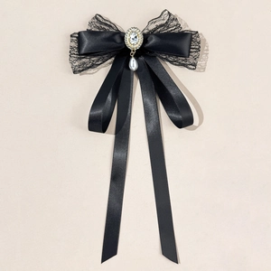 Detail of elegant black satin bow with lace trim, oval rhinestone and white pearl pendant
