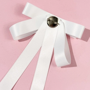 Close-up of a white satin bow brooch with a silver metal swivel pin on a pink background