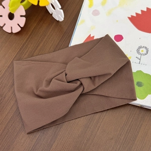 Detail of a brown twisted knit baby headband on a rustic wooden background with toys