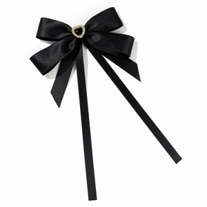 Détail macro d'un accessoire nœud en ruban noir avec pierre en cœur et bordure dorée