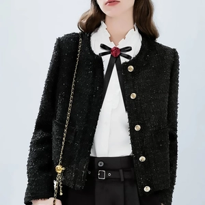 Detailed close-up of tweed jacket with golden buttons and rose ribbon bow accessory
