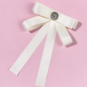 Elegant off-white satin bow brooch with vintage crystal centerpiece on pink background