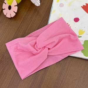 Close-up of pink elastic twisted headband for baby on a dark wooden surface background