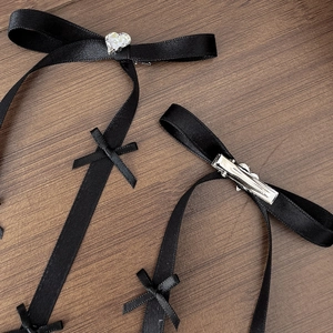Dettaglio del fermaglio per capelli a fiocco in raso nero con strass a cuore e clip