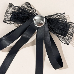 Elegant black lace bow brooch with pearl and rhinestone details on cream background