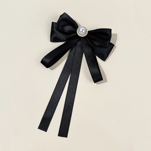 Detail of black satin bow tie with a large center pearl and elegant gold trimming