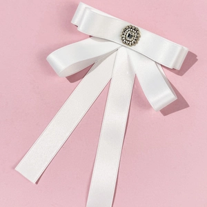 Macro detail of the white satin bow tie featuring a vintage crystal buckle and flowing ribbons