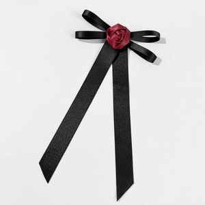 Detail of a handmade black ribbon bow brooch with a dark red fabric rose center flower