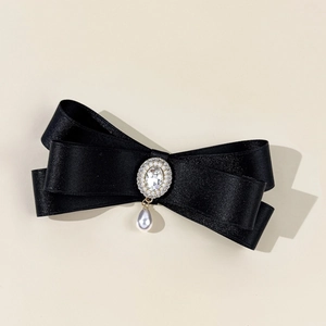 Close-up of black satin bow with rhinestone crystal center and teardrop pearl drop