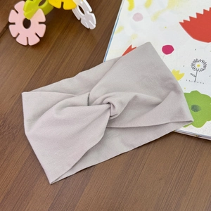 Close-up of baby twist headband in greige elastic knit fabric on wooden background