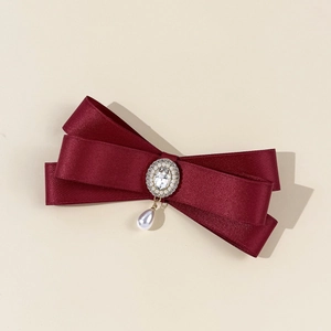 Detailed view of burgundy satin bow brooch with sparkling crystals and teardrop pearl