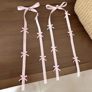 Dettaglio molletta a nastro in raso rosa con strass a cuore e piccoli fiocchi decorativi