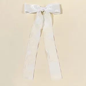 Dettaglio di un'elegante clip per capelli a fiocco in organza bianca con nastri