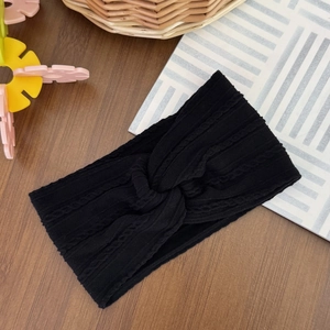 Detail of black cable-knit baby headband with stylish twisted knot and soft texture