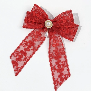 Detailed macro of red lace bow hair clip with faux pearl and gold-edged droplet pendant