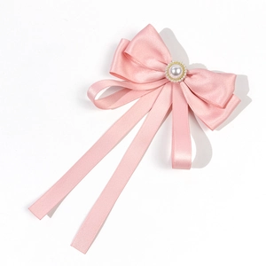 Detail of a light pink satin bow brooch with a central pearl and long ribbon streamers