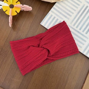 Close-up of red cable knit baby headband with twist knot detail on wooden background
