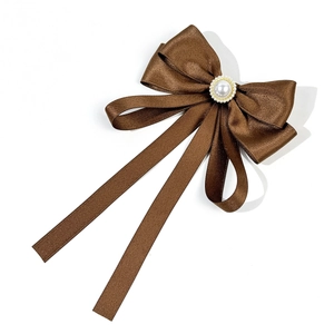 Detailed view of dark coffee satin bow tie with central pearl and elegant long ribbons