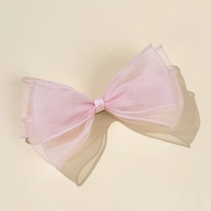 Detail of multi-layer pink tulle bow hair clip with translucent organza fabric texture