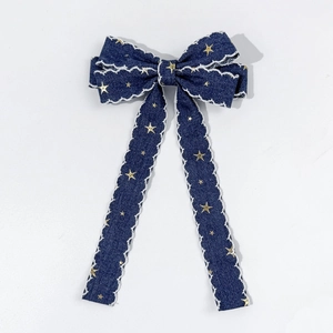 Detail of blue denim bow hair clip with gold stars and white lace scalloped edges
