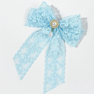 Detailed macro of a light blue lace bow hair clip with elegant pearl embellishments