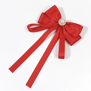 Detail of red satin bow brooch with imitation pearl, rhinestones and flowing long ribbons