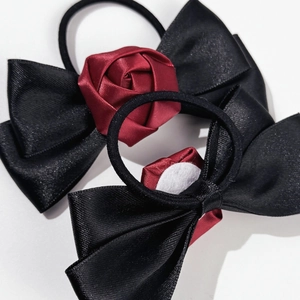 Détail de chouchous en satin avec nœuds et roses artisanales en noir et bordeaux