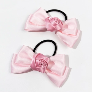 Détail de deux chouchous en satin rose avec nœuds et roses en soie faites à la main