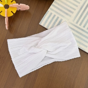Detailed view of white knitted baby headband with a twisted knot on wood background