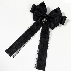 Détail du nœud papillon en satin noir avec dentelle et pendentif en forme de cœur