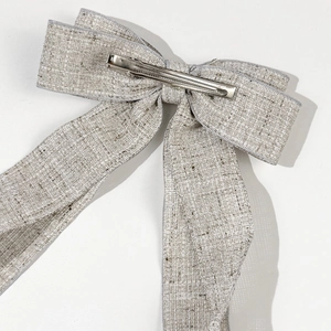 Elegant large beige linen bow hair clip with silver metal spring fastener on white background