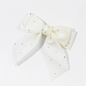 Détail de la pince à cheveux nœud blanc avec strass et texture en tissu à chevrons