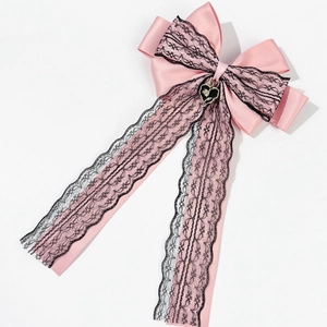 Détail de l'arc en satin rose avec dentelle noire et breloque en cœur à rose dorée