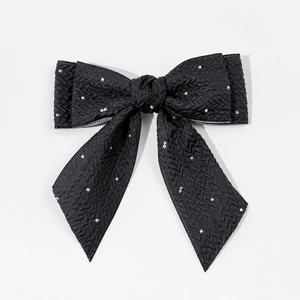 Gros plan détaillé d'une pince à cheveux nœud noir avec motifs à chevrons et strass