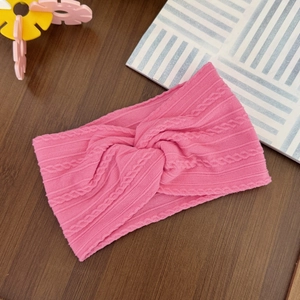 Close-up of pink knitted twist baby headband with delicate cable stitch pattern