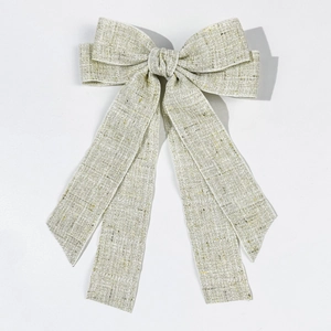 Macro detail of elegant cream and grey tweed bow hair clip with gold metallic threads