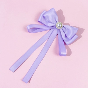 Detail of purple satin bow brooch featuring a central large pearl with gold bead trim