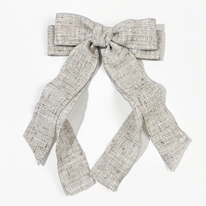 Detailed view of beige linen bow hair clip with long ribbons on white background