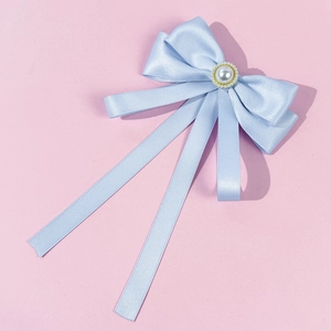 Detail of light blue satin ribbon bow with center faux pearl and gold beads on pink background