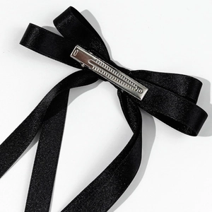 Detail view of the silver metal duckbill clip on the back of a black ribbon hair bow