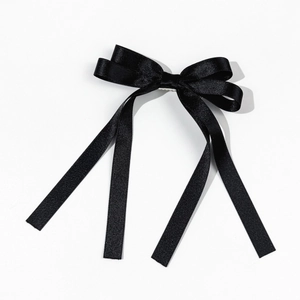 Detail of elegant black satin bow hair clip with four long flowing ribbons for women