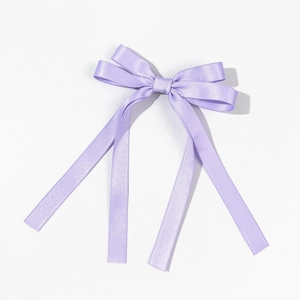 Detail of light purple satin bow hair clip with long ribbons and smooth texture