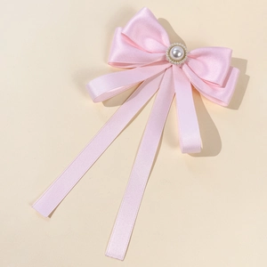 Detail of pink satin bow brooch with large pearl centerpiece and long ribbons